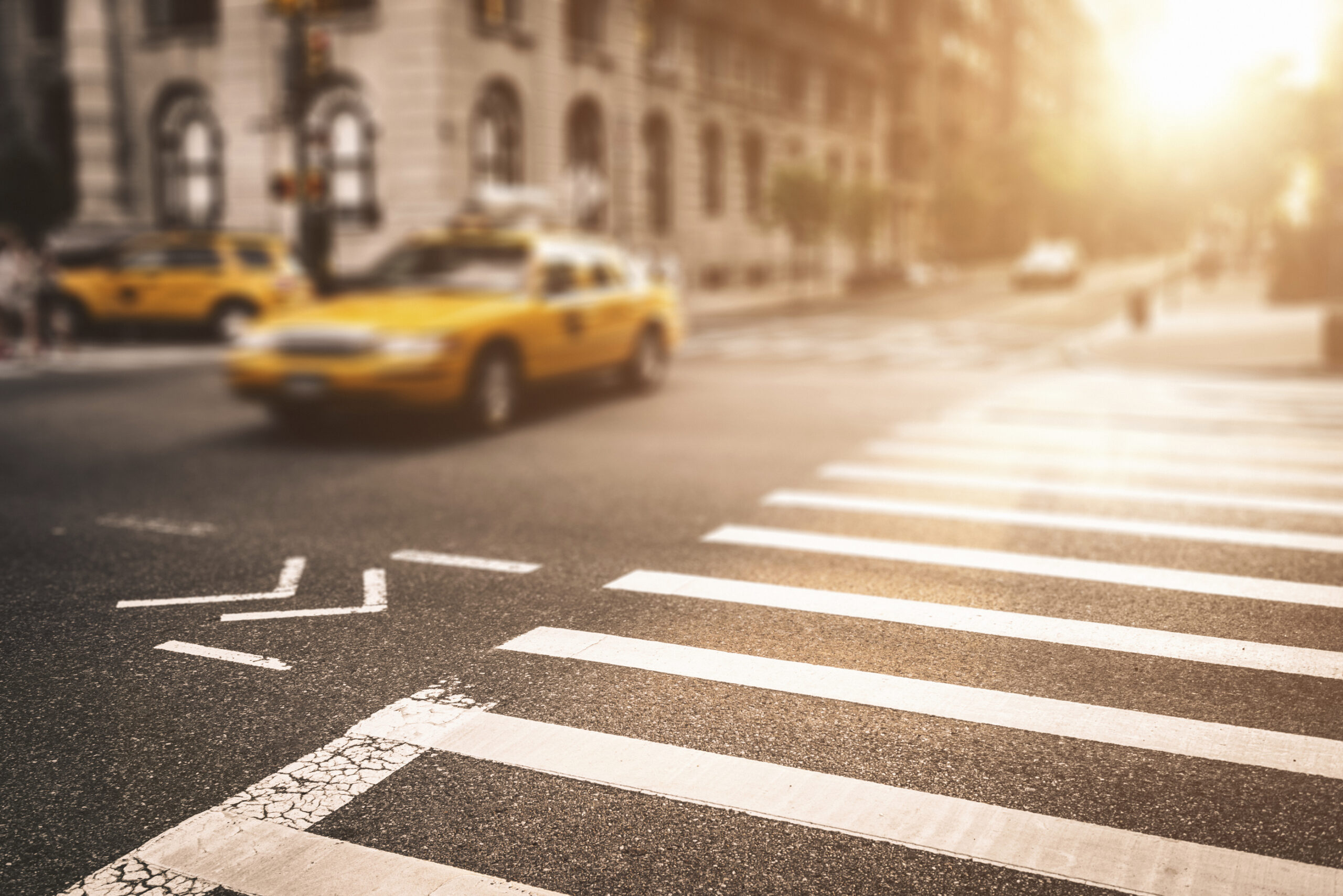 A busy intersection in Manhattan in the morning featuring a taxi.